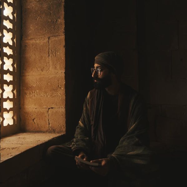 Person meditating peacefully near a window with soft light.